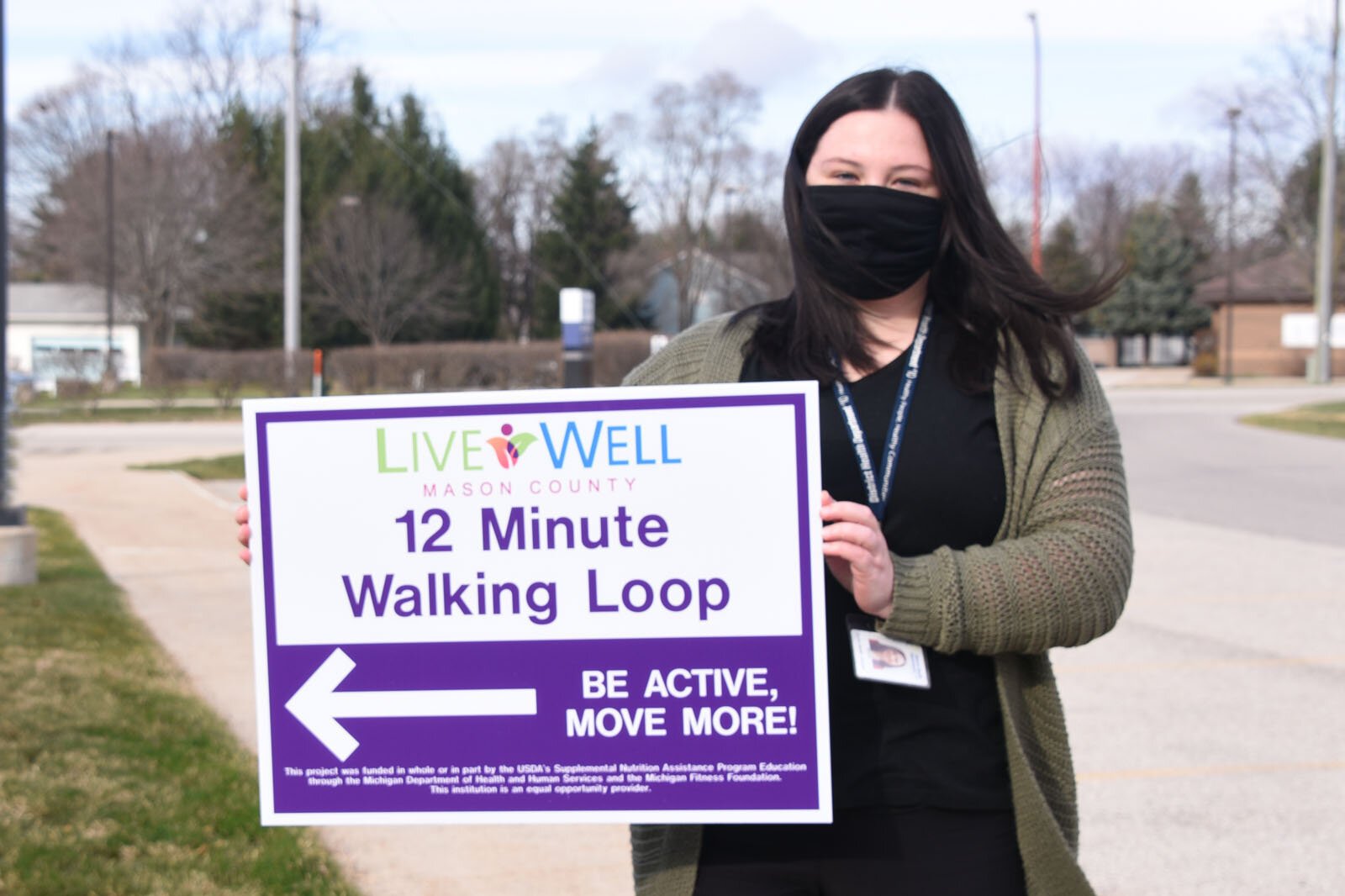 Erin Barrett holds a walking trail sign in Ludington.