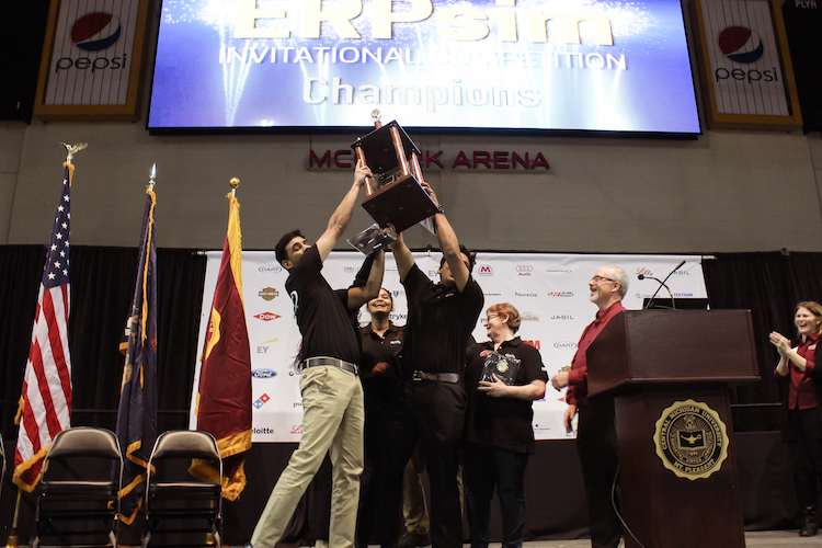 Dart Team 1 team mates Bernad Nelson and Manjunath Madarampalli hoist their teamâs trophy in the air after they received first place in the championship round of the 7th Annual ERPsim Invitational Competition