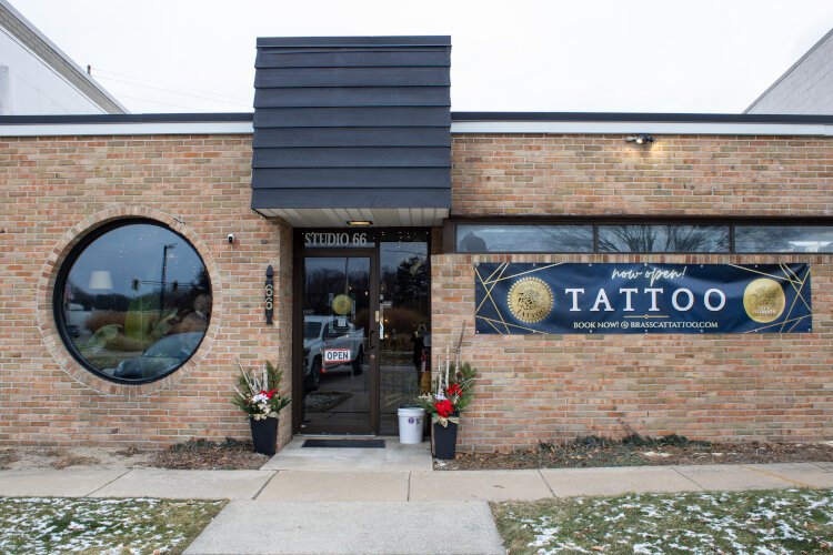 The Brass Cat Tattoo Studio building with now open sign hung in Midland