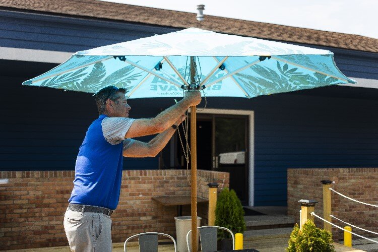 Rekeweg helps open up umbrellas on the back patio at Frick's.