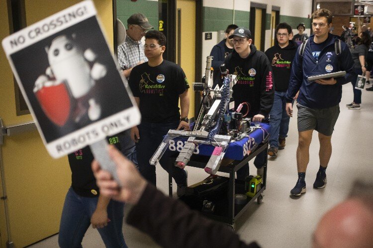 Team members of "Rockefeller Robotics" of Mt. Pleasant High School move their robot through a hallway.