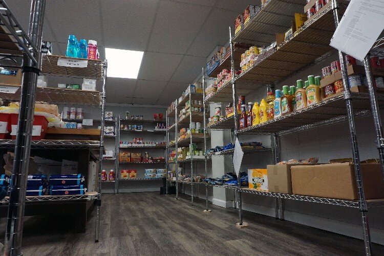 The shelves are stocked with foods such as cereal, canned goods, nuts, and more.