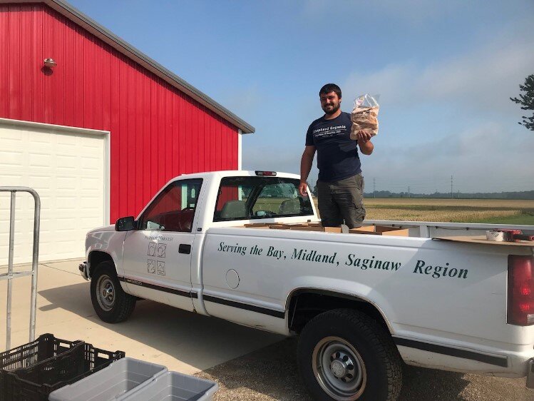 Shepherd Organics Owner - Tyler Shepherd loading the Hidden Harvest truck with a donation of locally raised and processed organic chicken.