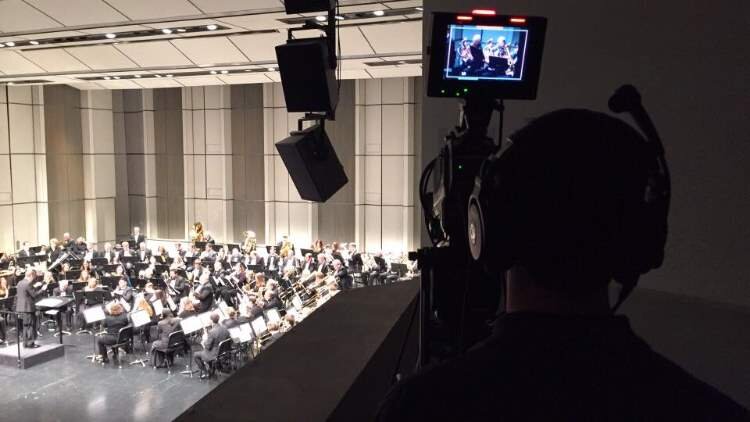 Volunteer operates a camera at a Midland Concert Band performance in the Center for the Arts.