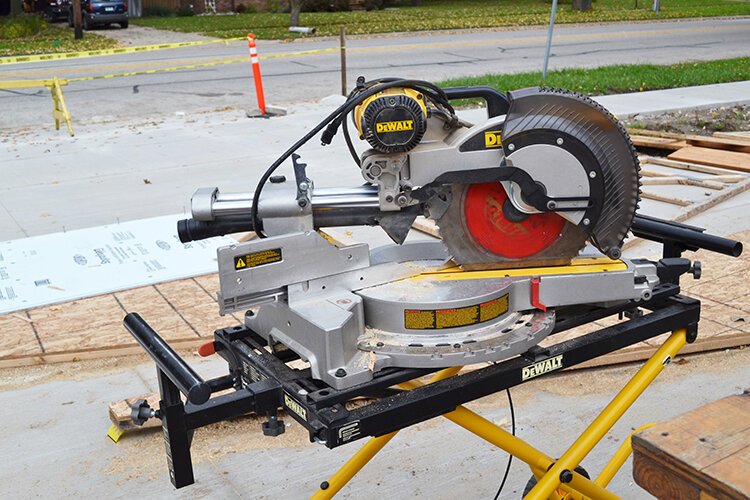 Participants use a range of tools to build walls, roof beams, and interior components, braving the weather while other MPS students sit in the classroom.