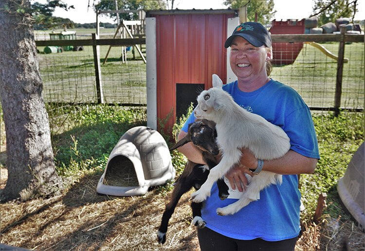 Amanda King of Grandma's Pumpkin Patch holds two baby goats, Snowy and Blipster.