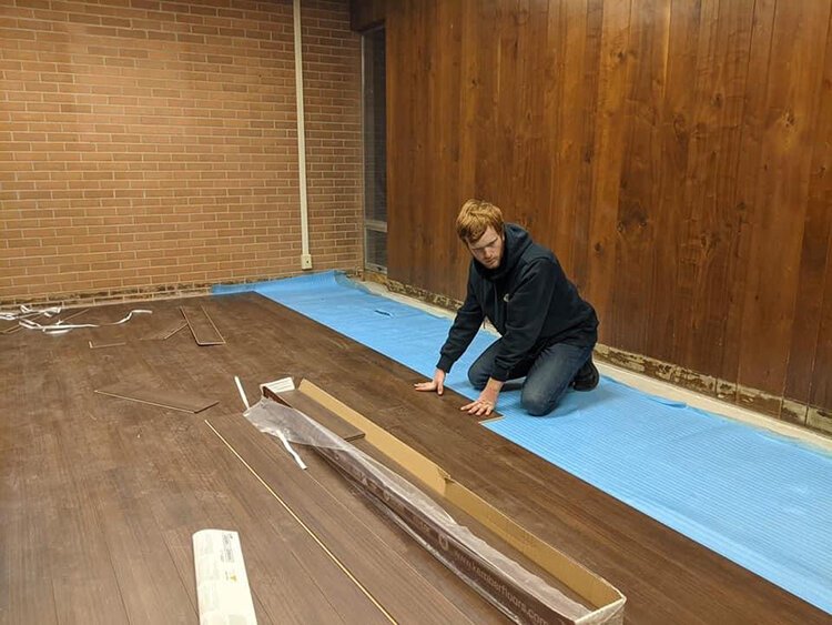 Brenden Bass lays the new floor at the Children's Grief Center.