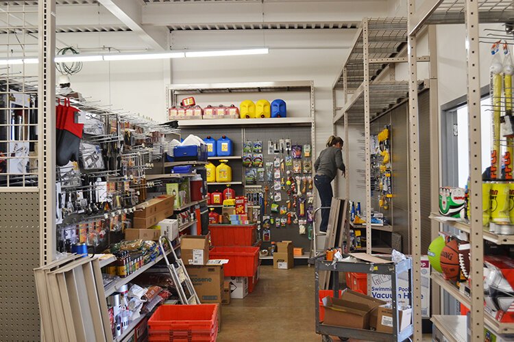 Store associates stock shelves while construction work and painting continues in the background. 