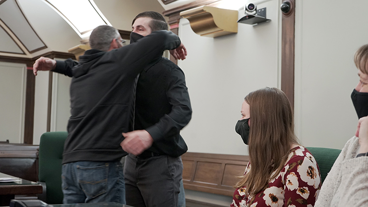 Wygant, center, hugs his friend Buddy Yancer, left, while MiHOPE coordinator Brionna Varner, center-right, and probation officer Lisa Budreau, off-right, watch.