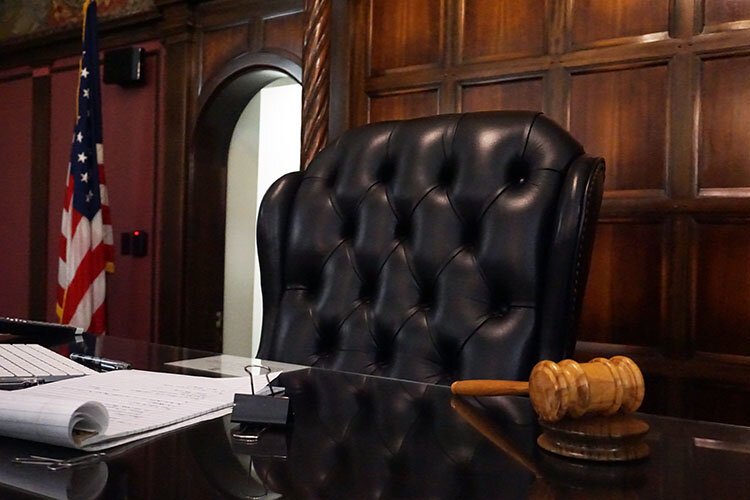 Because of COVID-19, the court meetings are also held synchronously on Zoom. The only people in the courtroom are Judge Carras and the clients, possibly accompanied by a family member.