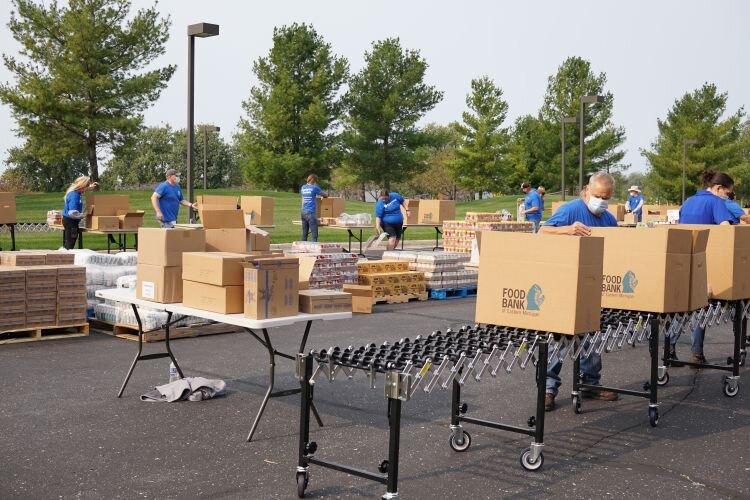A safe and socially-distant crew of Corteva employees pack boxes of food.