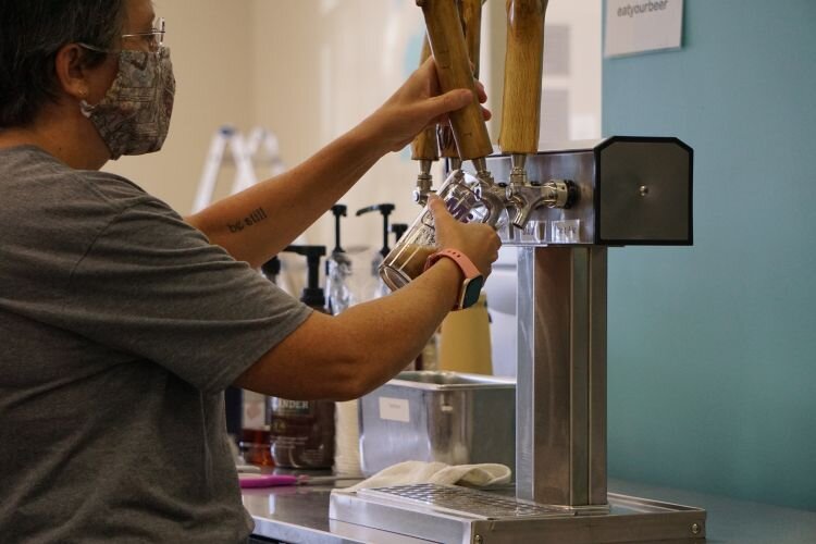 Suzanne pours a beer for customers.