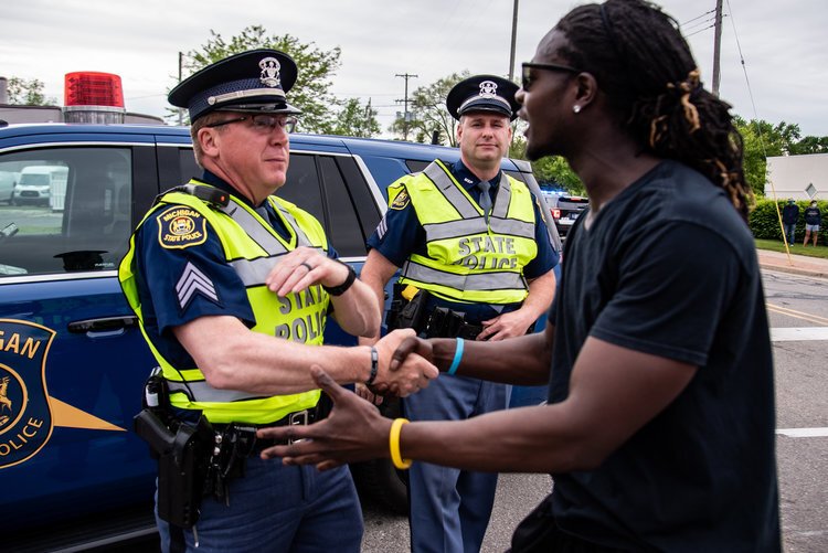 Trokon Jayqua, right, thanks police officers during a march to protest the death of George Floyd and social injustice June 1 on Mission Street in Mount Pleasant, MI(PC: Isaac Ritchey)