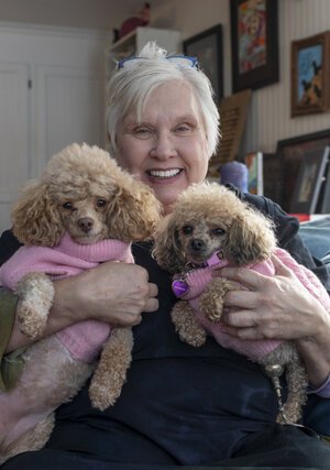 Sue Bergeson sits in her living room which overlooks Gray Lake, holding her two dogs, Andromeda and Alsyon. 