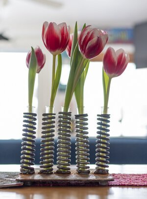 An unconventional flower vase Bergeson made using rusty screws and test tubes sits on a table. 