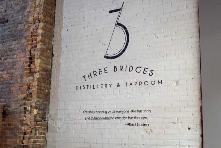 The Three Bridges logo was designed to mirror the blend of a few things including a guitar and martini skewer.