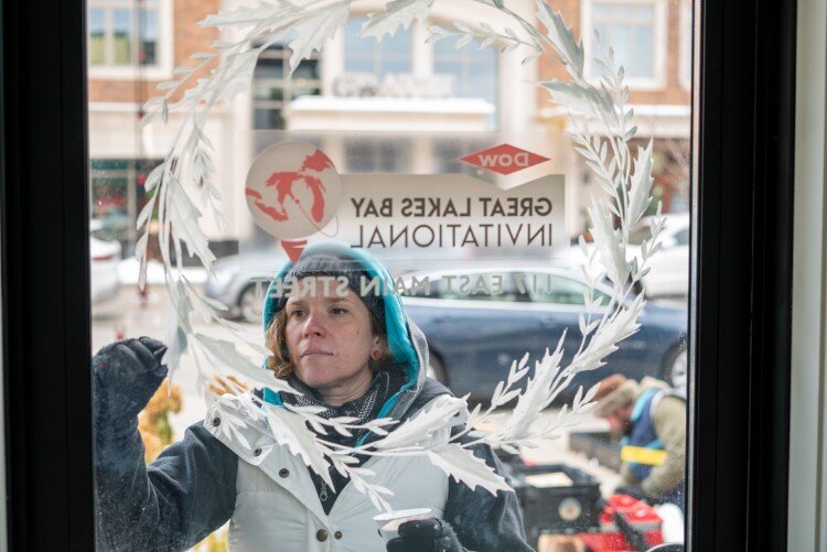 Mary Thiefels paints the door of the Dow Great Lakes Bay Invitational.