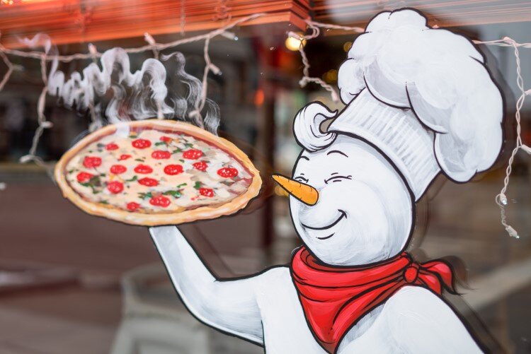 A steaming hot pizza can been seen in the window of Pizza Sams.