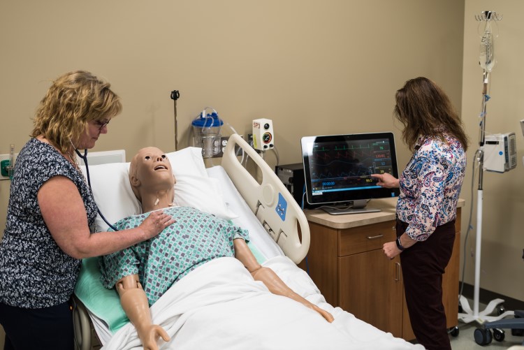 Joyce Cook, senior simulation specialist and another nurse practice a mock procedure.