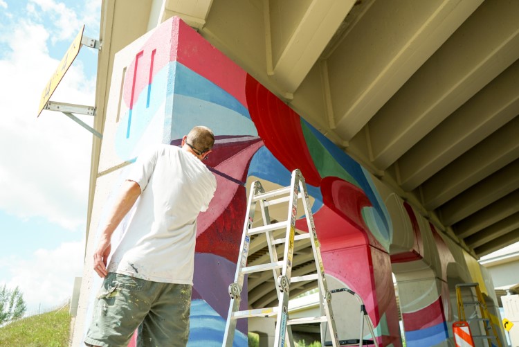 Piotrowski working on the US-10 bridge mural in Midland.