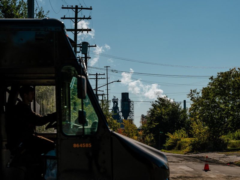 In Detroit, a truck drives on Jefferson Ave. while smoke billows from Zug Island.