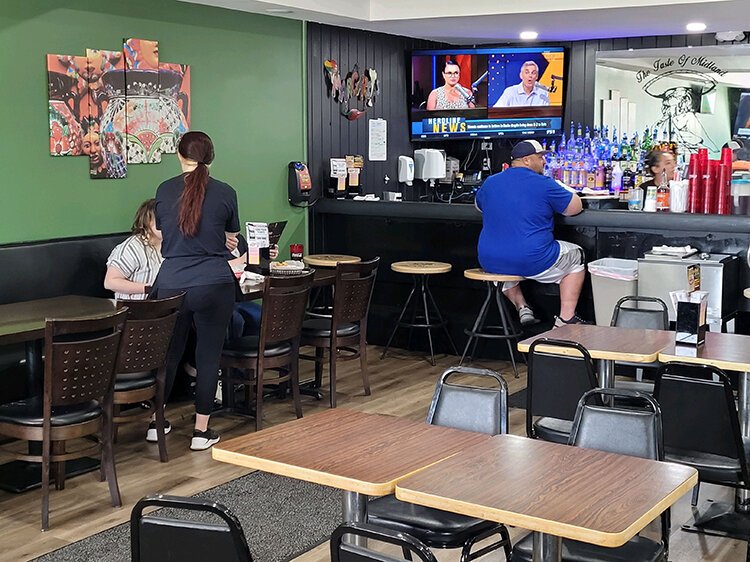 The restaurant has a classic Tex-Mex theme with upbeat colors like orange and green and features contrasting sophistication with darker trim and bar area seating.