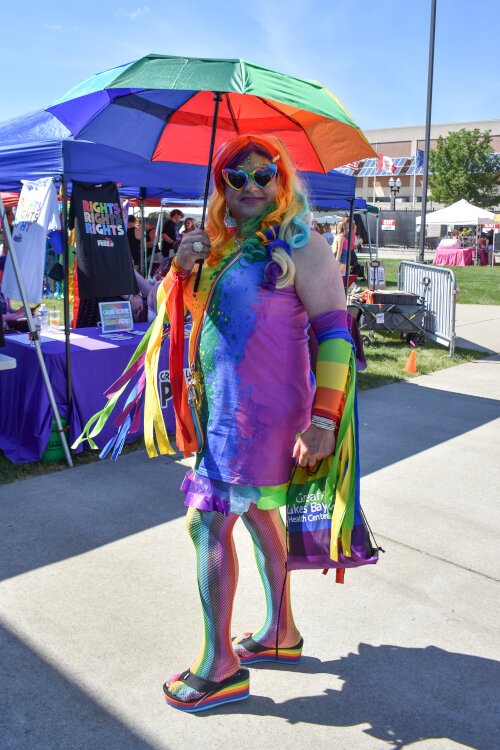 An attendee poses for a photo with a rainbow umbrella at the Great Lakes Bay Pride Festival