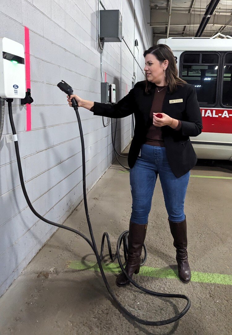 Amy Bidwell, Dial-A-Ride manager, demonstrates new EV charging station.