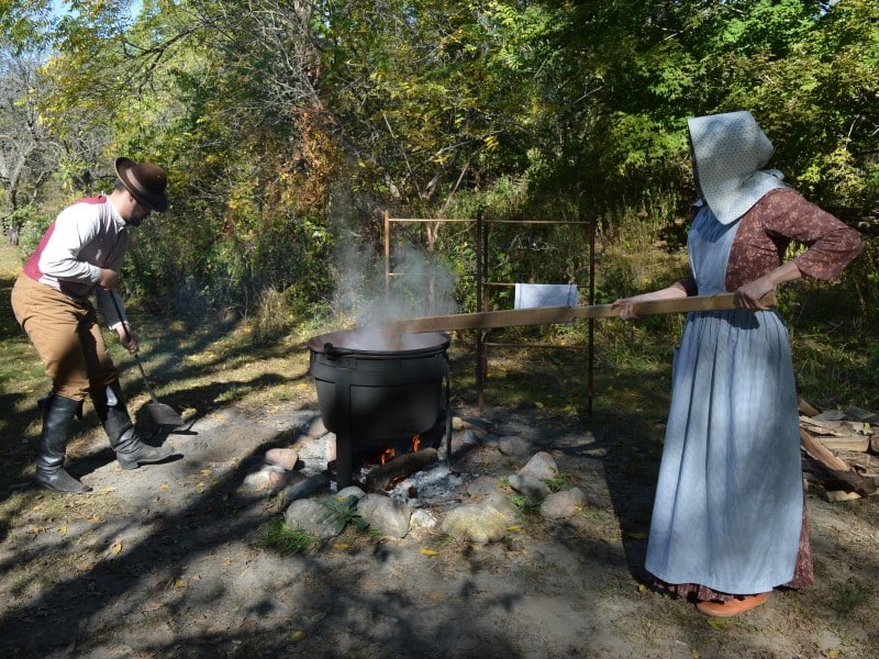 People in period costume churning butter