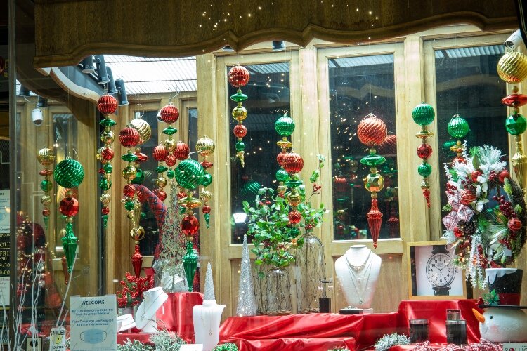 Traditional red, green, and gold ornaments hang above the jewelry in the Herman Hiss display window.