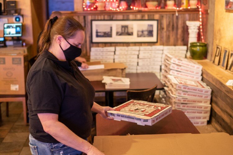 Brooklyn Boyz employee Sarah Miller wears a mask while packaging up an order for delivery.