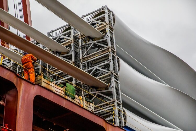 The stevedores remove and re-use the fixtures that secure the blades to the freighter during transport.