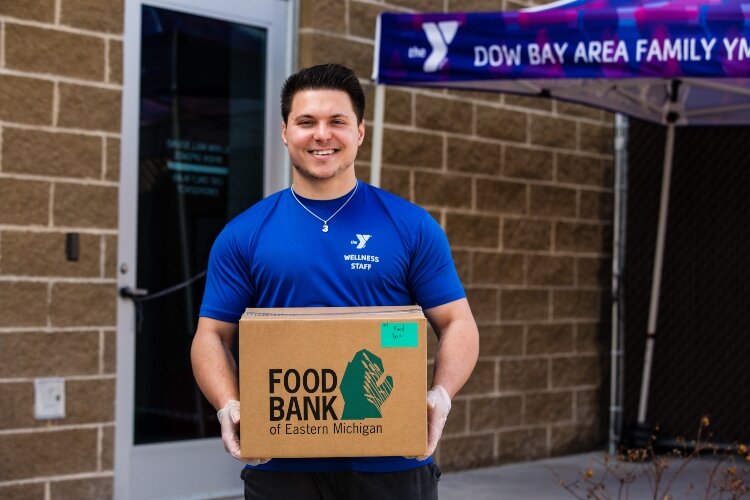 Zack Booth from the Dow Bay Area Family YMCA carries one of the food boxes available as part of the program.
