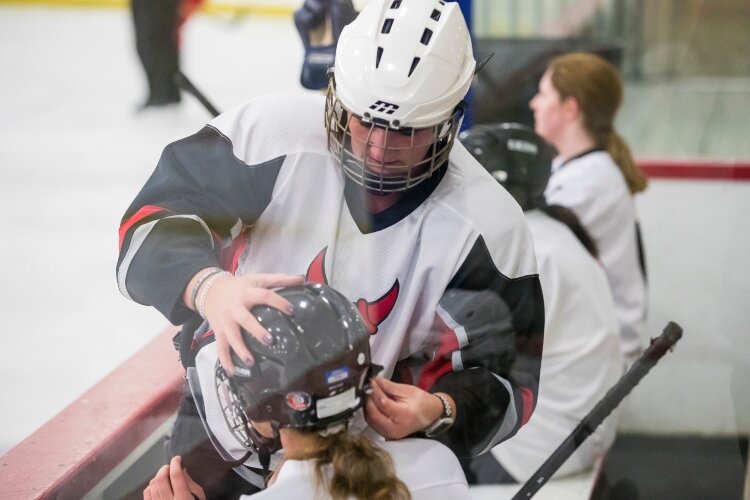 The women help each other become familiar with the equipment and rules.