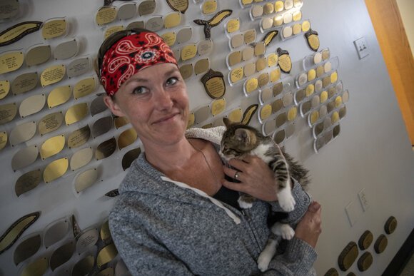 Becki Maes, clerk at the Bay County Animal Control and Care Center, poses with one of the cats at the center.