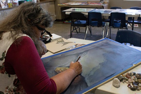 Julie Tyslicky works with a colored pencil to create a detailed rock drawing.