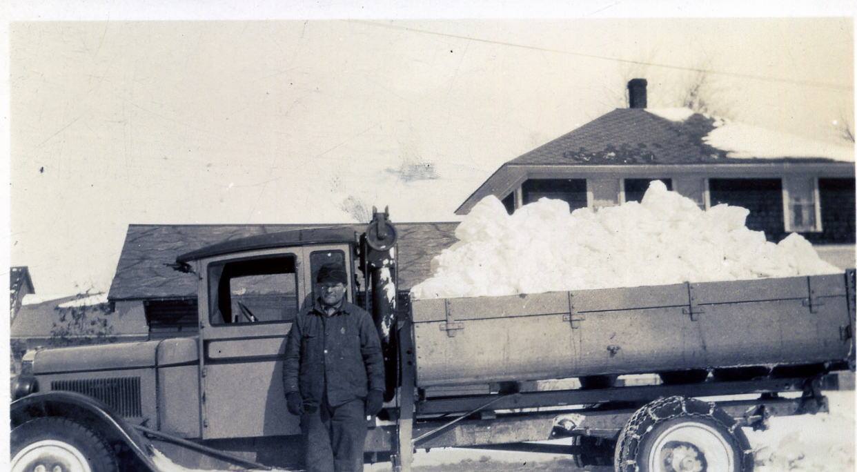 Serenus Johnson standing in front of his snow removal truck. 