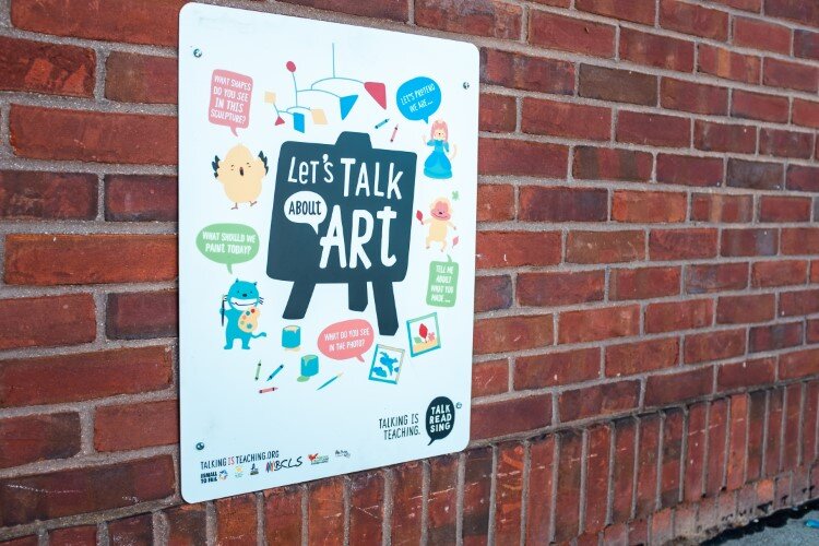 A sign in the park guides parents through conversations about art with young children. 