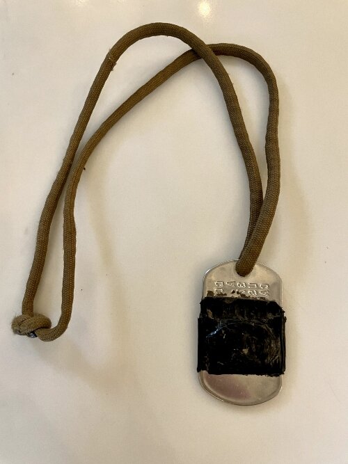 A saint medal is taped around these dog tags.