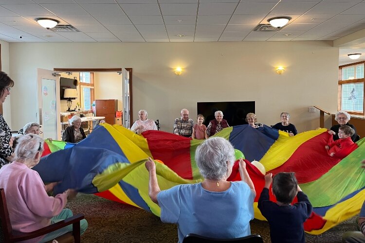 A physical activity, such as holding a parachute up for the kids to run under, gets everyone moving during the visits.