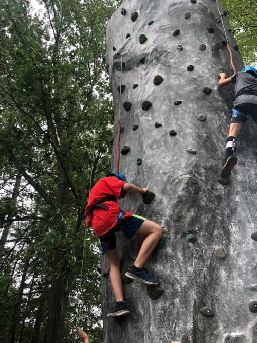 Camper activities include climbing a rock wall.