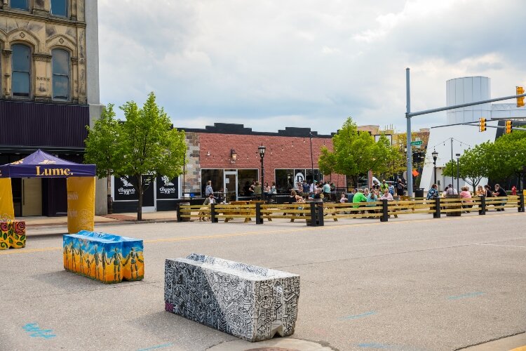 Visitors enjoy food and beverages at outdoor tables in Bay City's East Side business district.