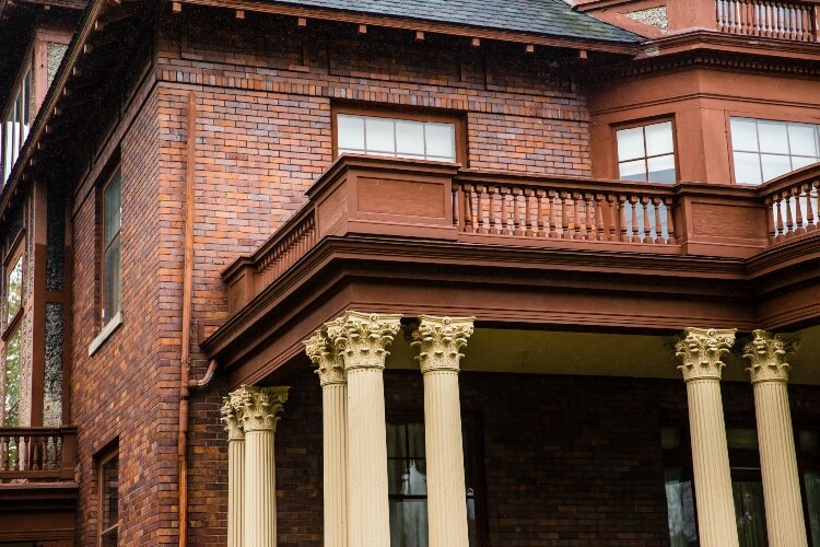 Multiple bay windows and an open upper balcony highlight the façade.