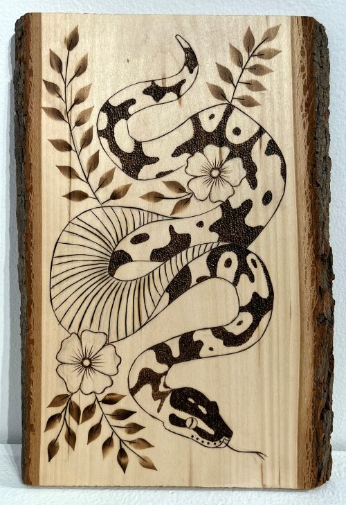 Julia Shepard, of Evermore Tattoo Gallery, created this Scorched Serpent pyrography. In pyrography, artists use a heated pen-like metal tool to create burn marks.